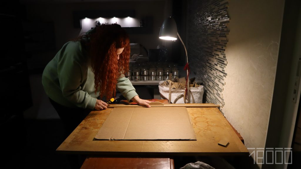 Волонтерка відрізає смуги картону для гноту свічки
