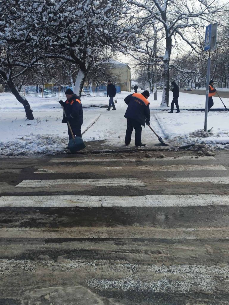 Комунальники, які чистять сніг