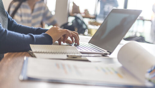 жінка пише за ноутбуком на столі