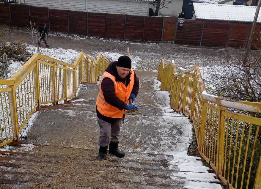 Комунальник посипає сходи