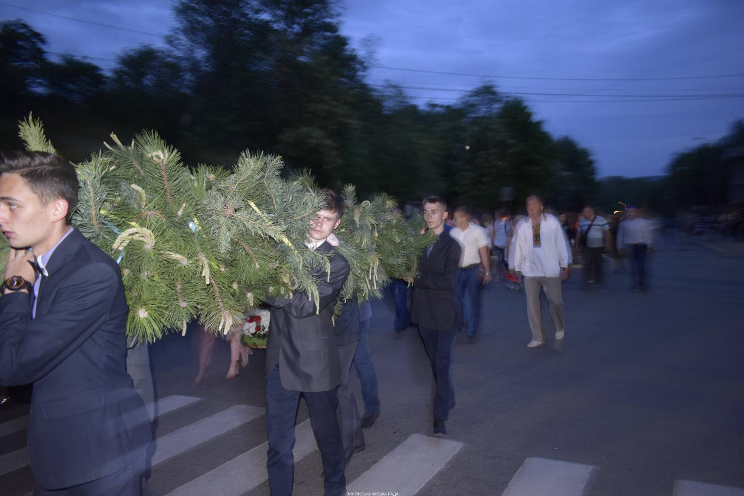 Люди несуть вінок із сосни