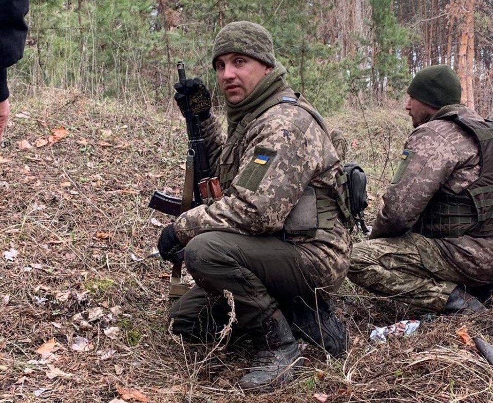 Чоловік у військовій формі в лісі з рушницею
