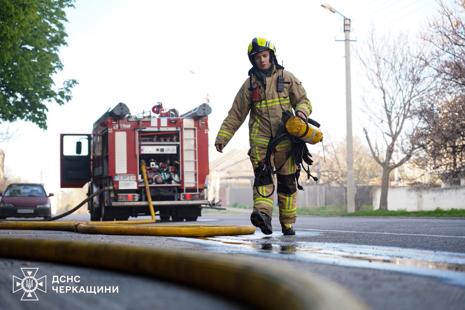 Рятувальник у спорядженні та з балоном у руках йде від автомобіля